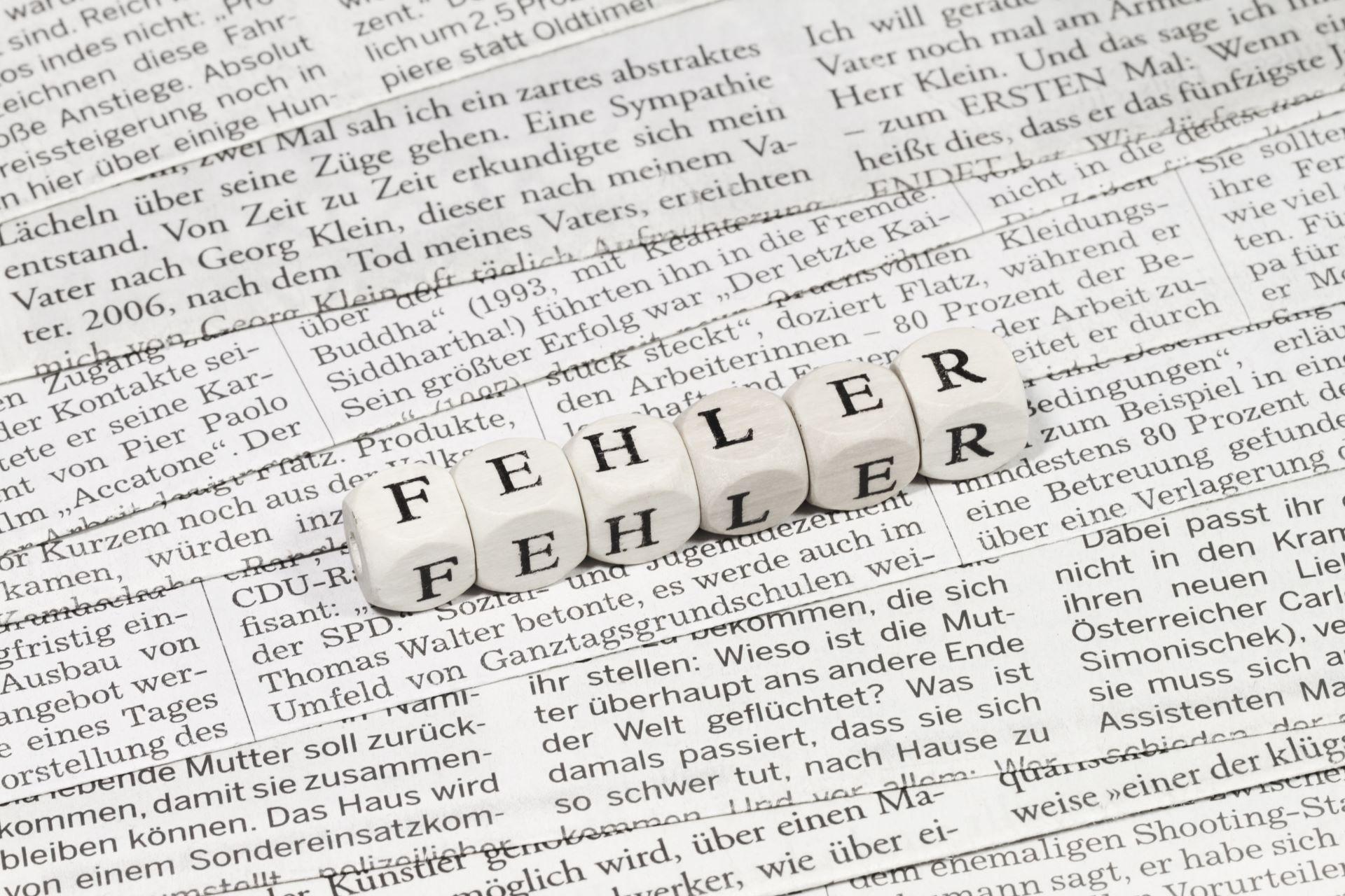 Würfel mit Schriftzug Fehler auf Zeitungstext